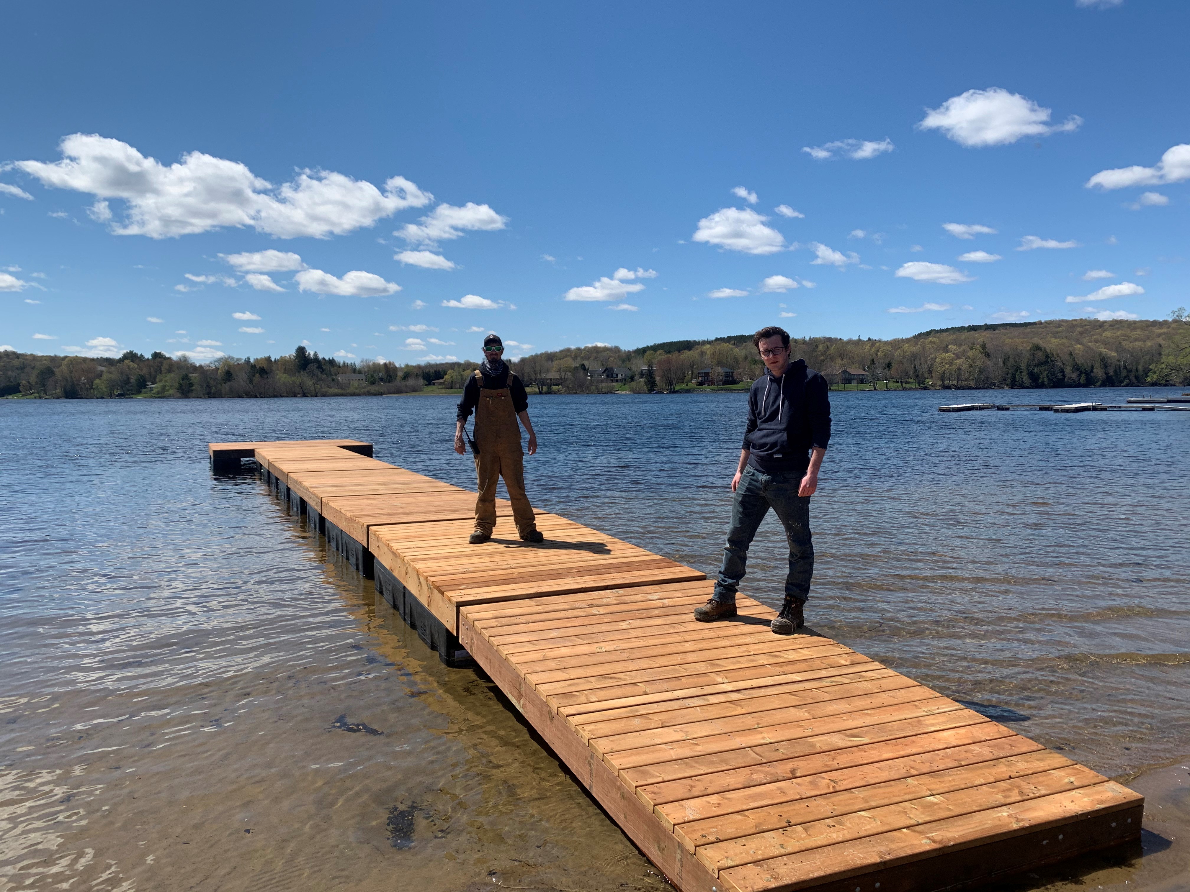Two people standing on a new dock at Rotary Beach. The dock has a slight ramp to access other sections.