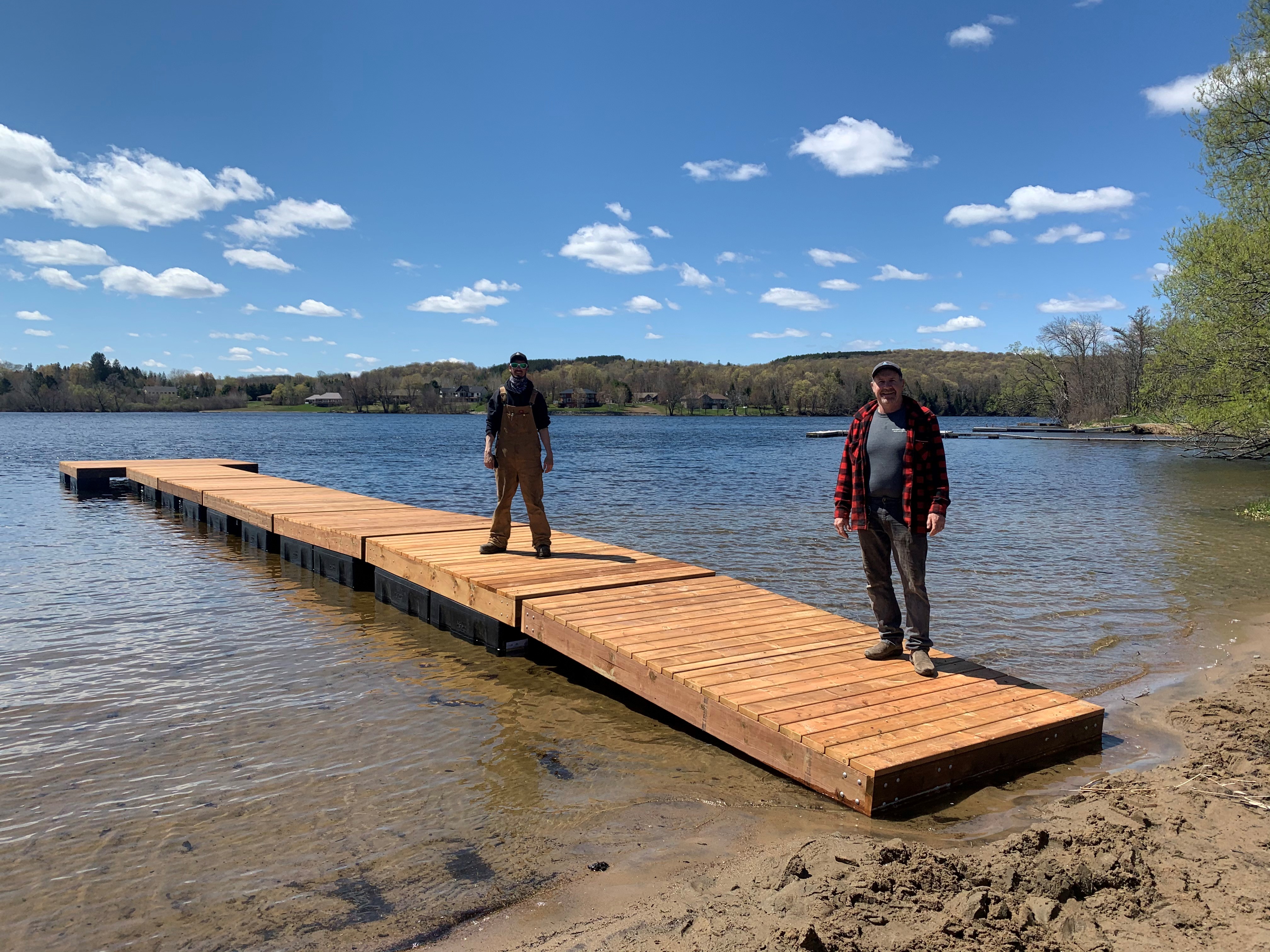 Two people standing on a new dock at Rotary Beach. The dock has a slight ramp to access other sections.