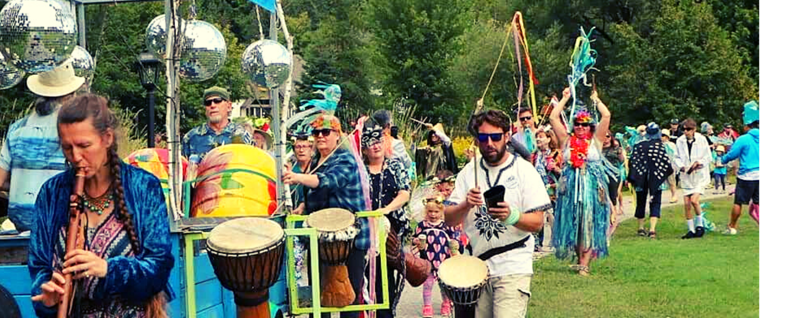 Parade of people carrying drums and dressed in a variety of bright, cheerful costumes.