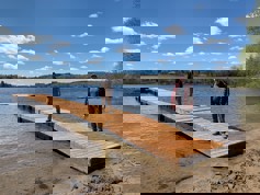 Two people standing on a new dock at Rotary Beach. The dock has a slight ramp to access other sections.