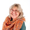 Image of Wendy Wood, sandy blonde hair, red framed glasses, wearing an orange woven scarf.