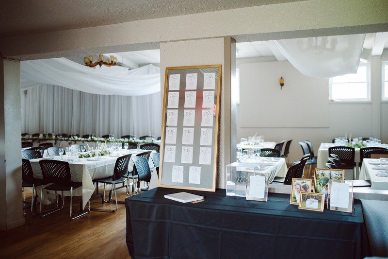 Reception area  entering the main hall. Shoes a board with table assignments and pictures on a table.